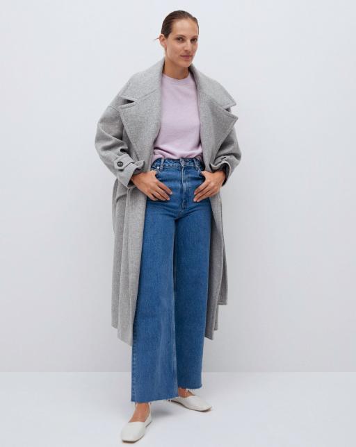 standing model wearing pink sweater, jeans and long gray overcoat