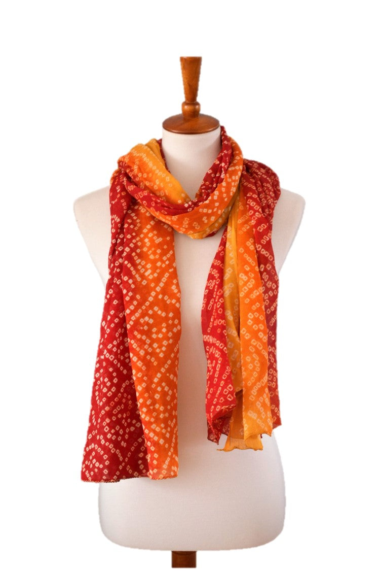 red to golden ombre scarf draped on form in front of white wall