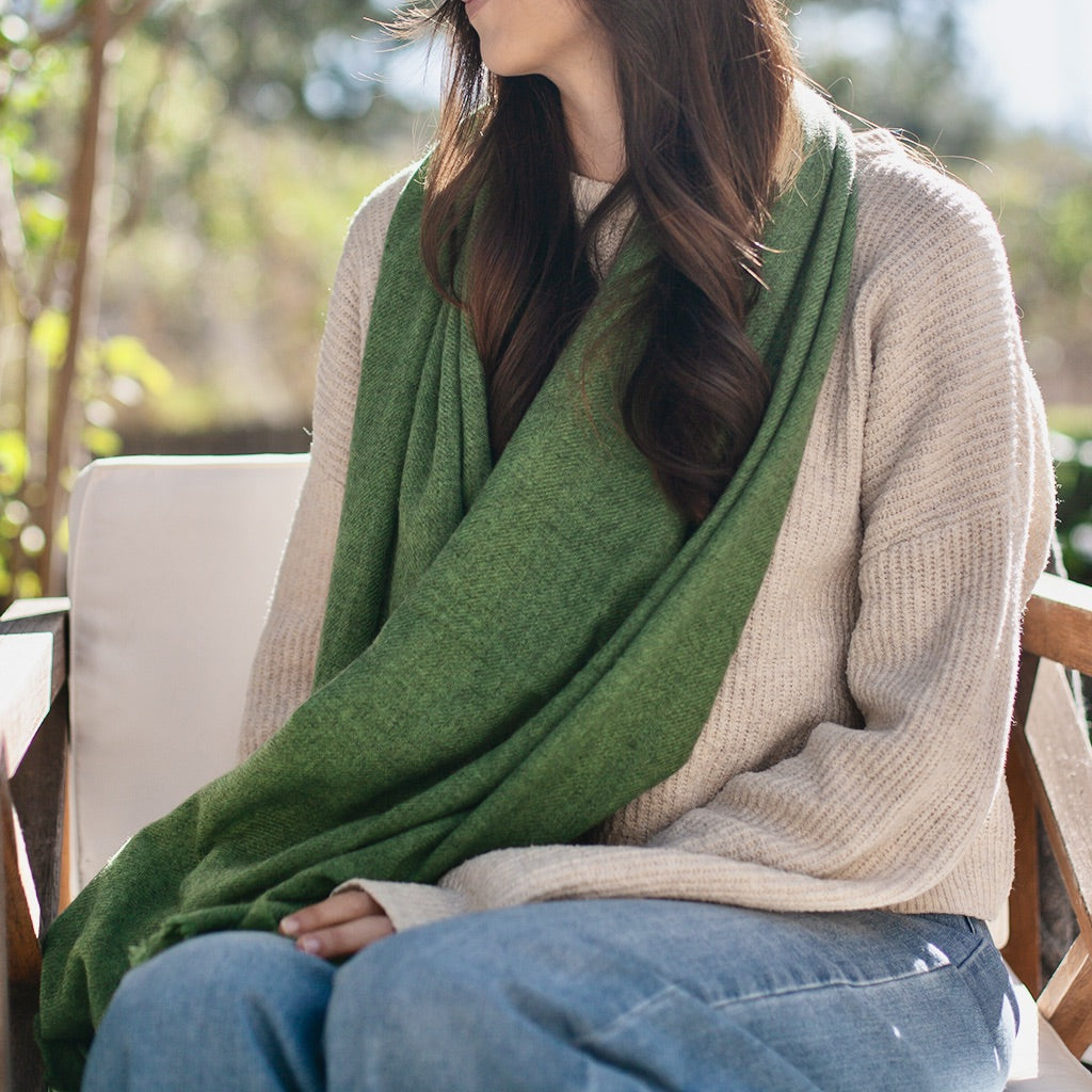 woman sitting outside with a green wrap scarf around her shoulders