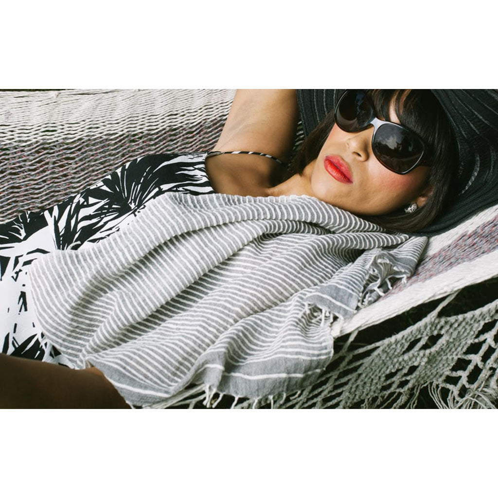 lady lounging with gray and white striped scarf over shoulder in a hammock