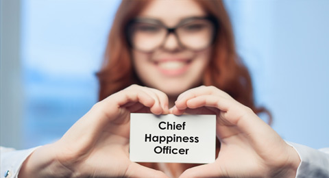 Woman holding card that says "Chief Happiness Officer" in heart shaped hands